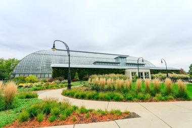 Photo of the entrance of Garfield Park Conservatory with curved pathway surrounded by plantings on both sides.