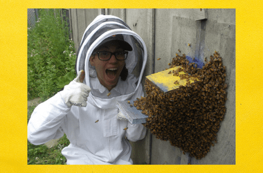 A photo of Dr. Rachael Banoan next to a bee colony. She is smiling.