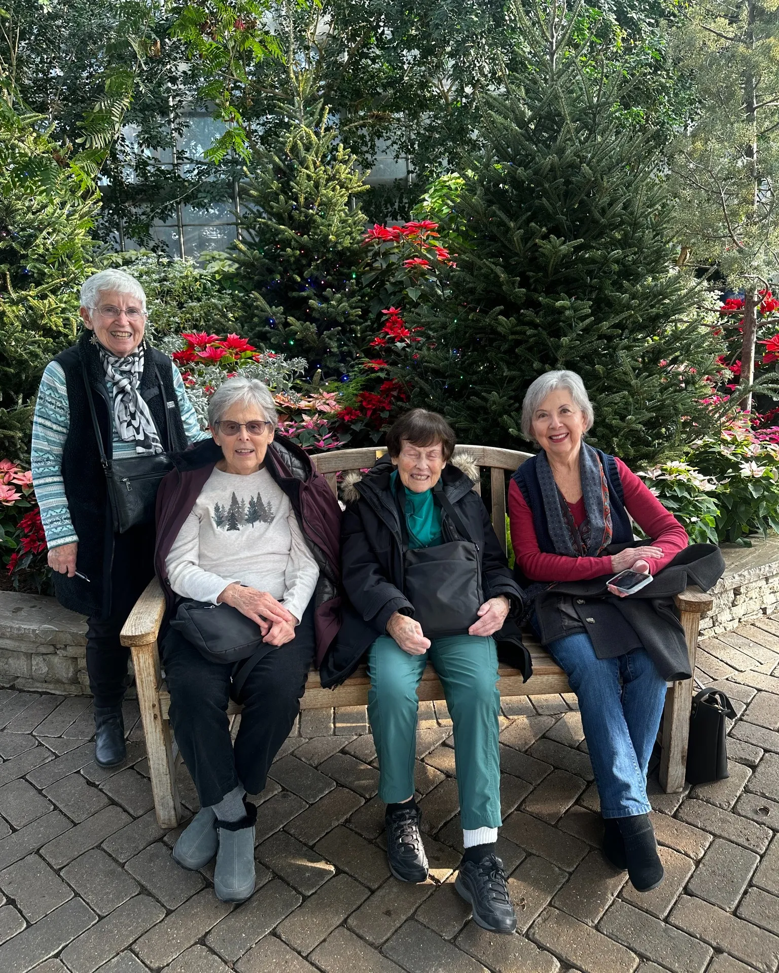 Group of adults posing for a photo with three people on a bench and one standing in the Show House