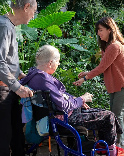 Guests, one being pushed in a wheelchair, exploring the garden.