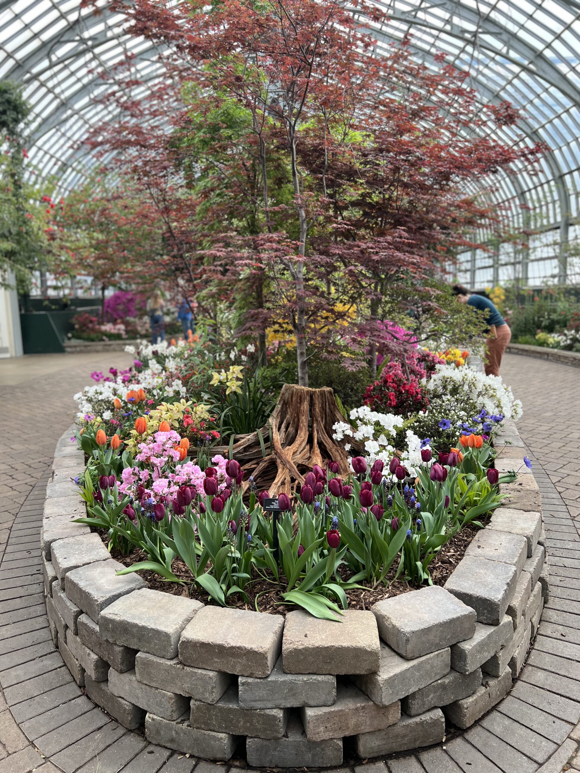 Temporary center bed full of flowers and small trees in the middle of the Show House.