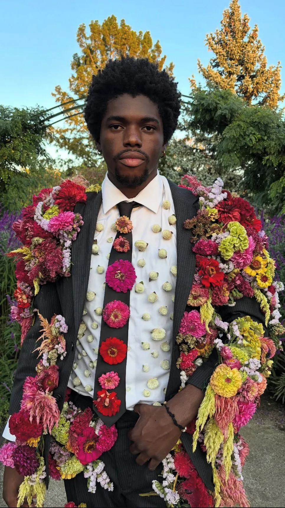 A man wearing a suit adorned with flowers.