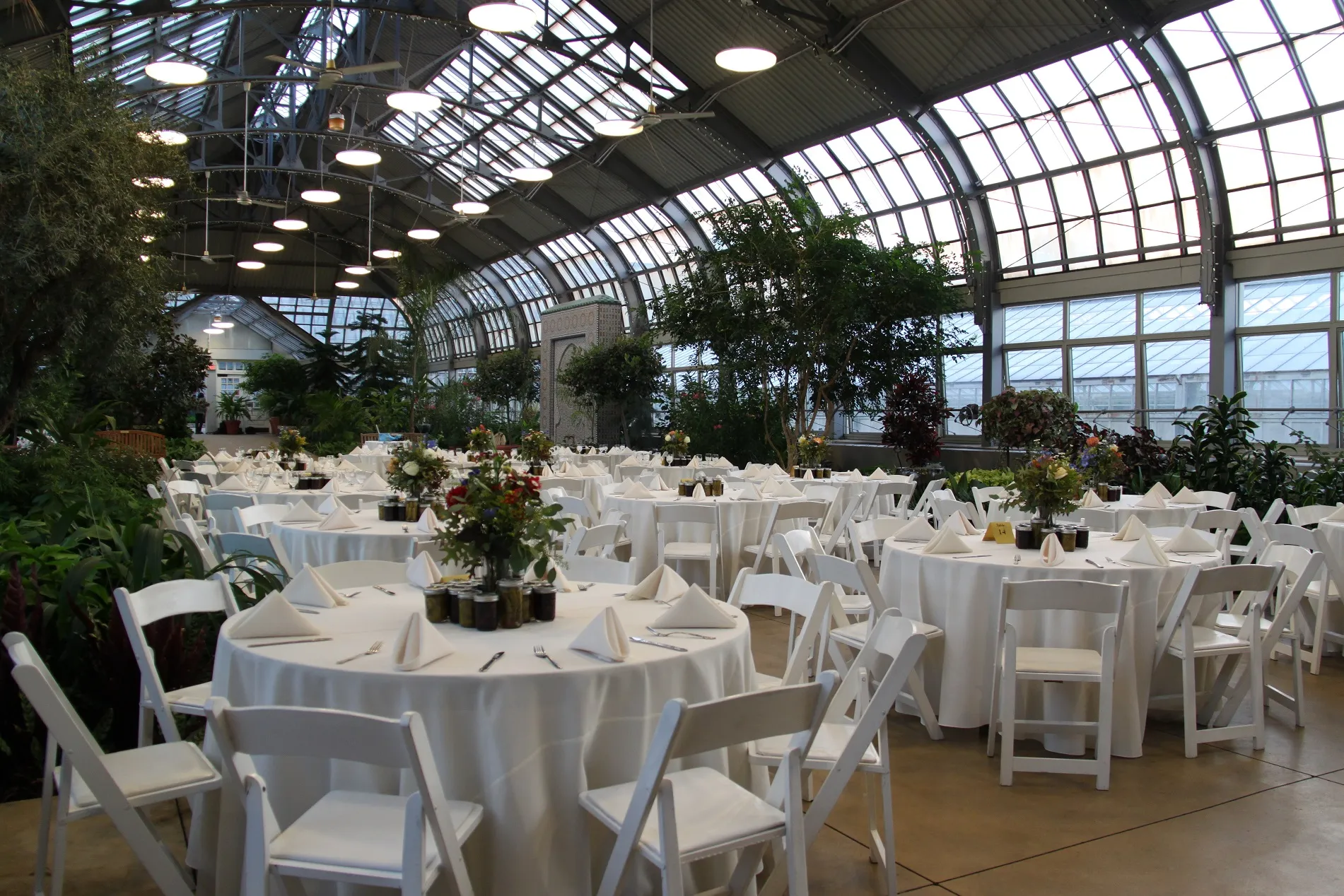 Round tables set up with white tablecloths and place settings in Horticulture Hall