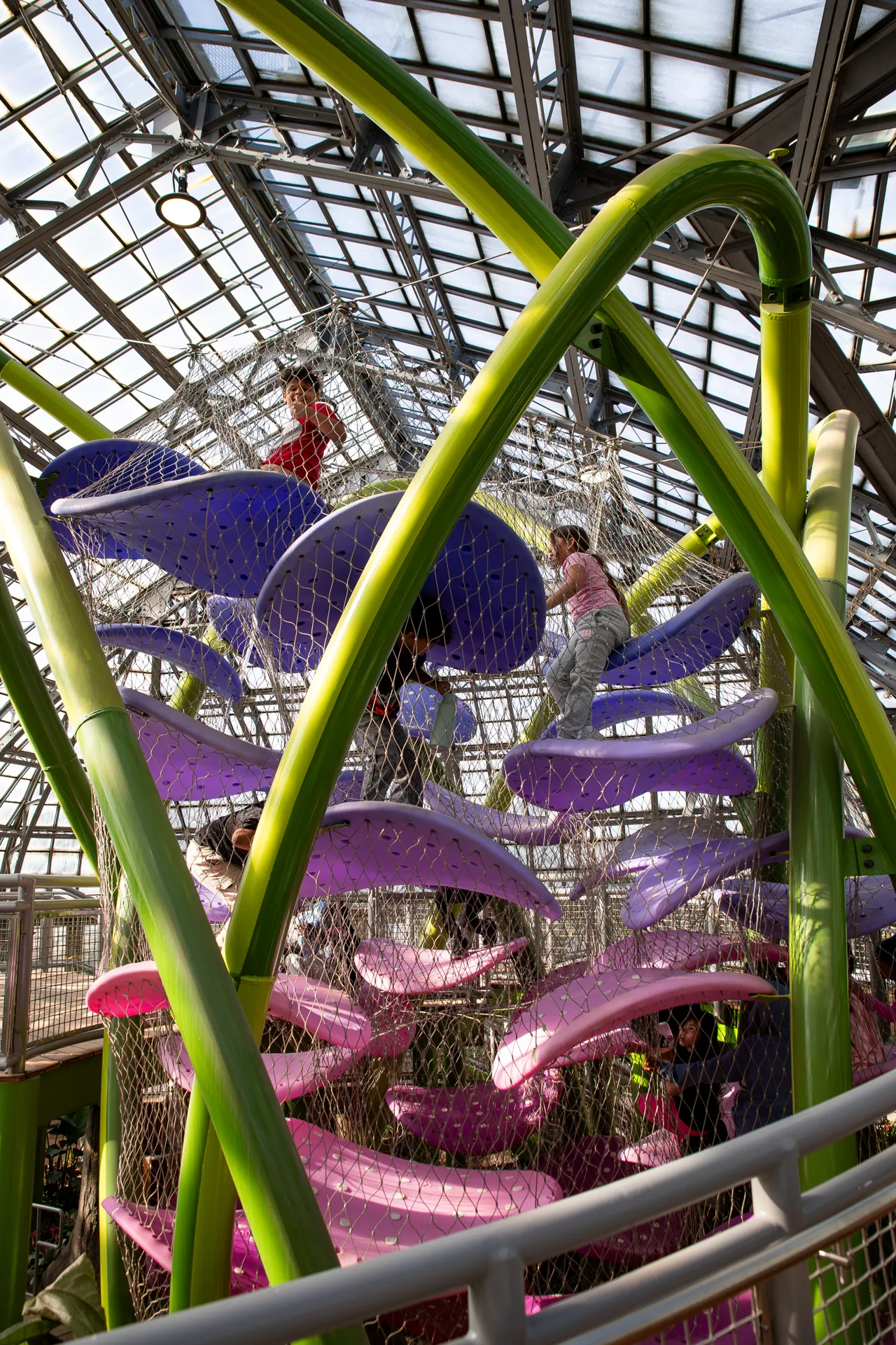 Children climbing on a pink, purple and green climbing structure in the Children's Garden.