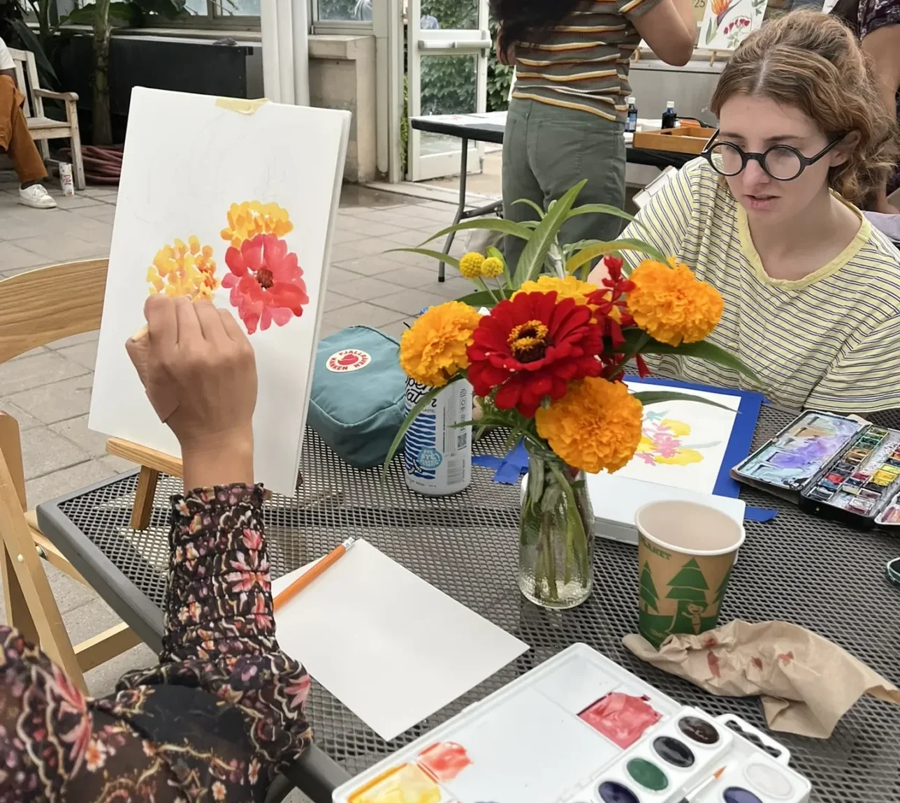 Adult painting flowers at a table.