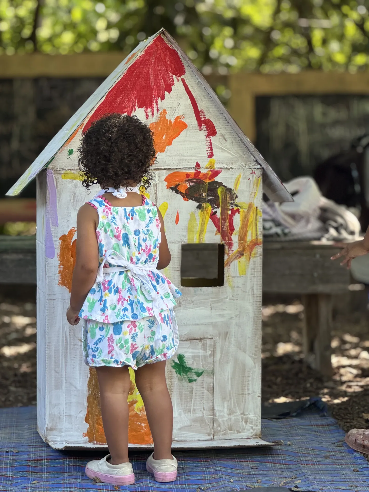 Child painting a White House outside in the Play and Grow Garden