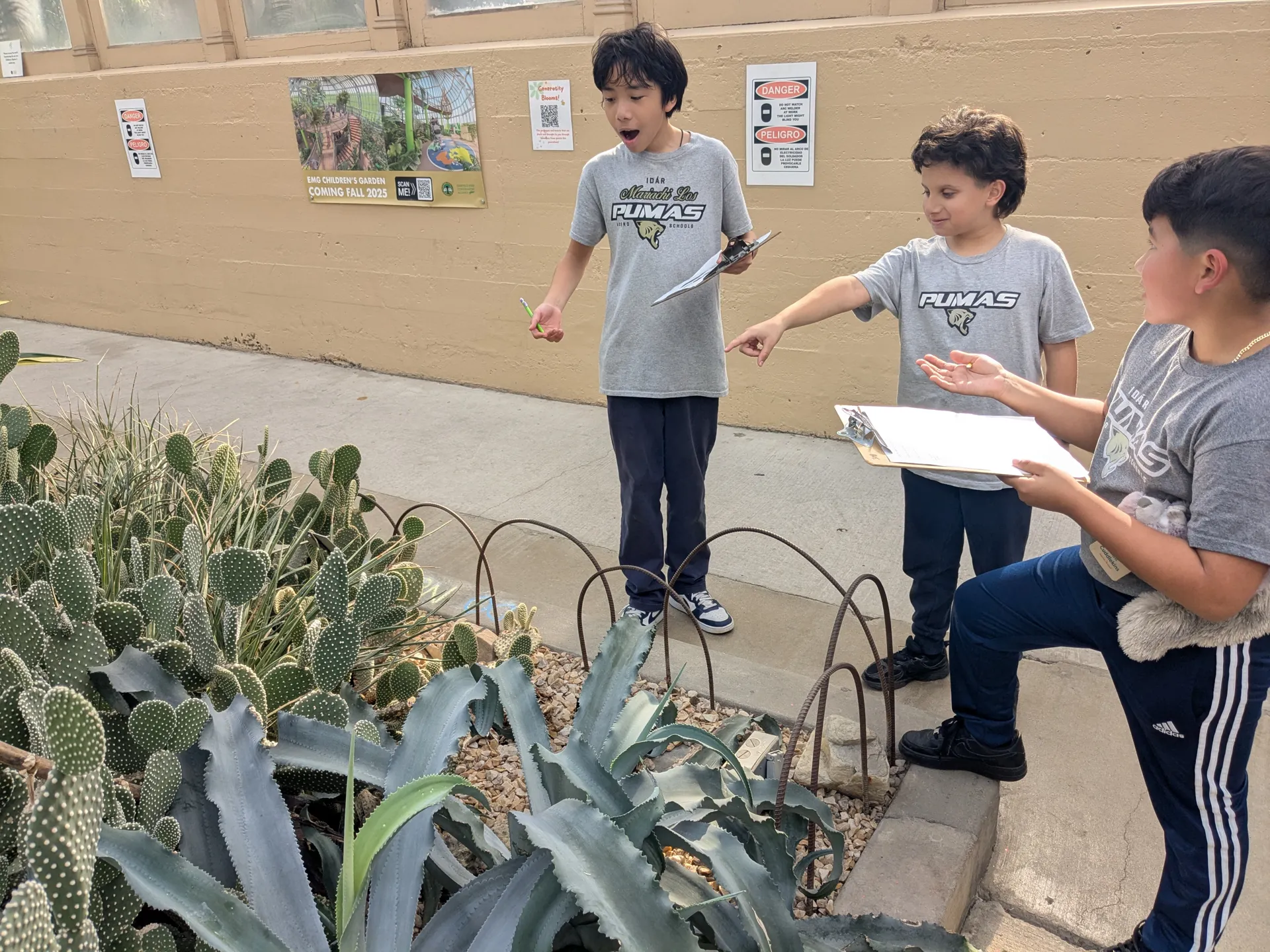 School children pointing to a plant in the desert house