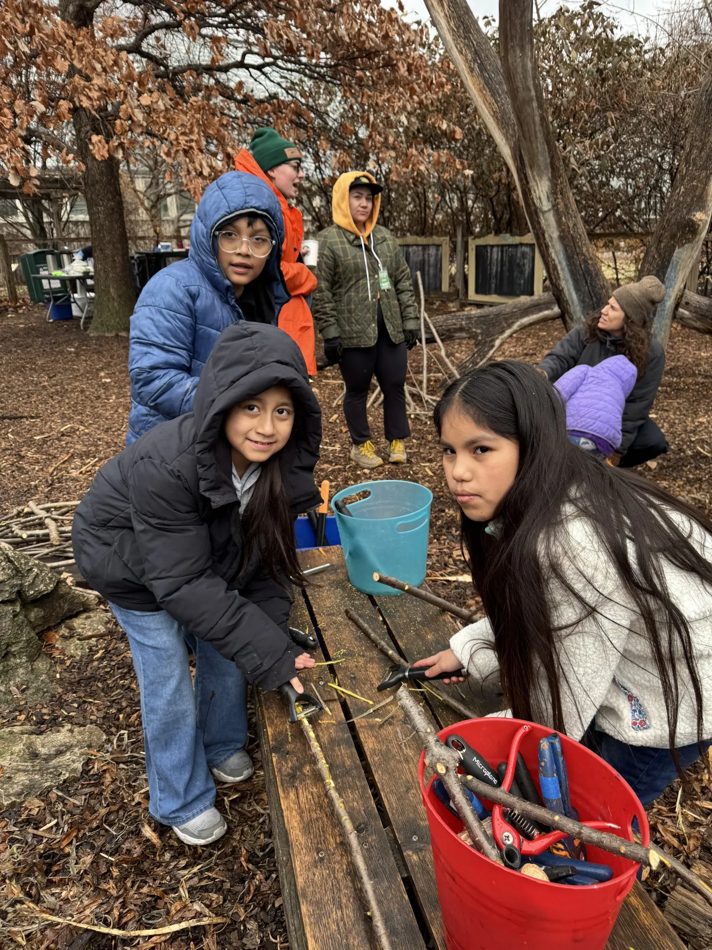 Children playing outside with sticks in Play and Grow Garden