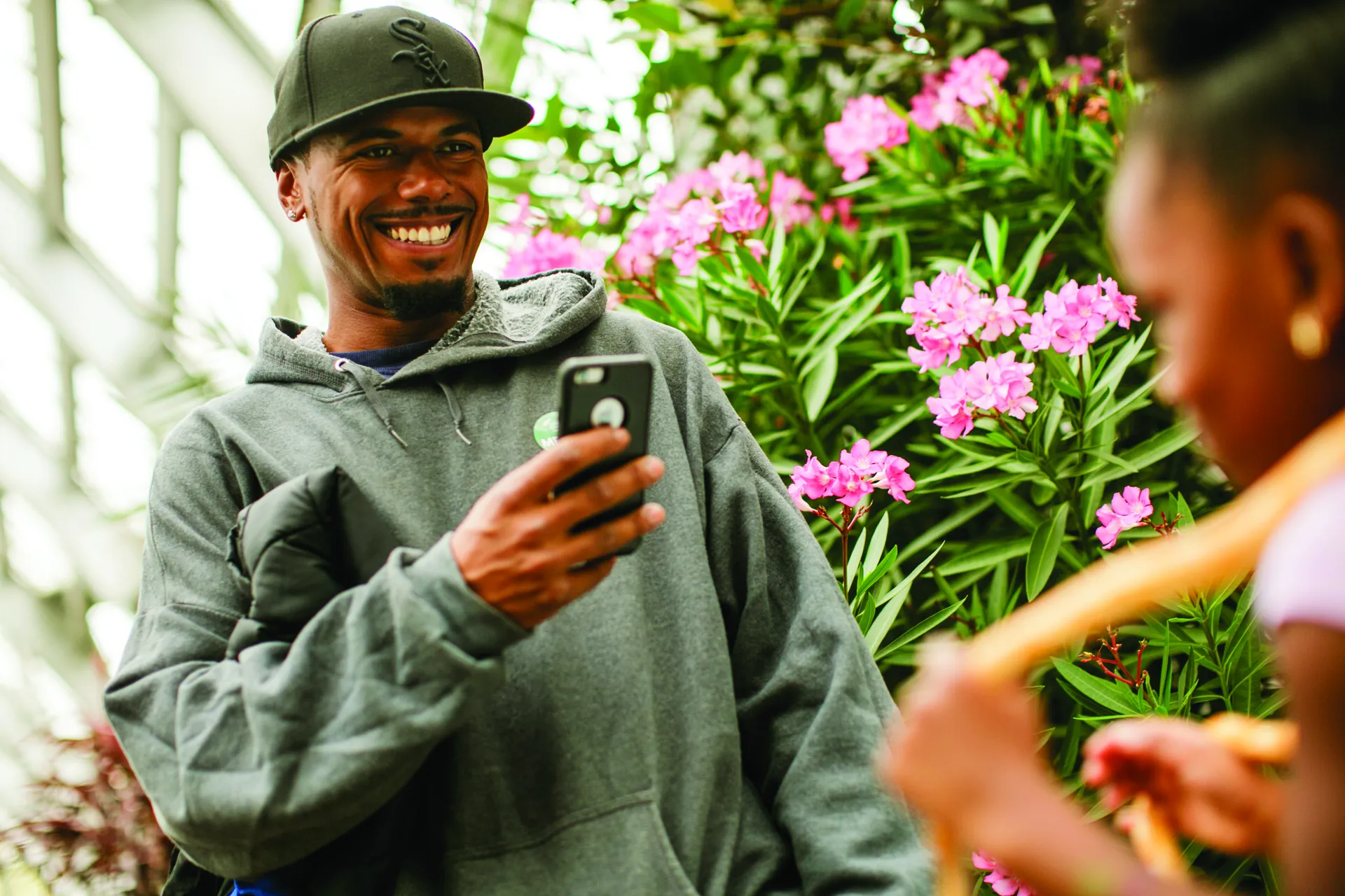 A smiling man uses his phone to take a photo of a girl