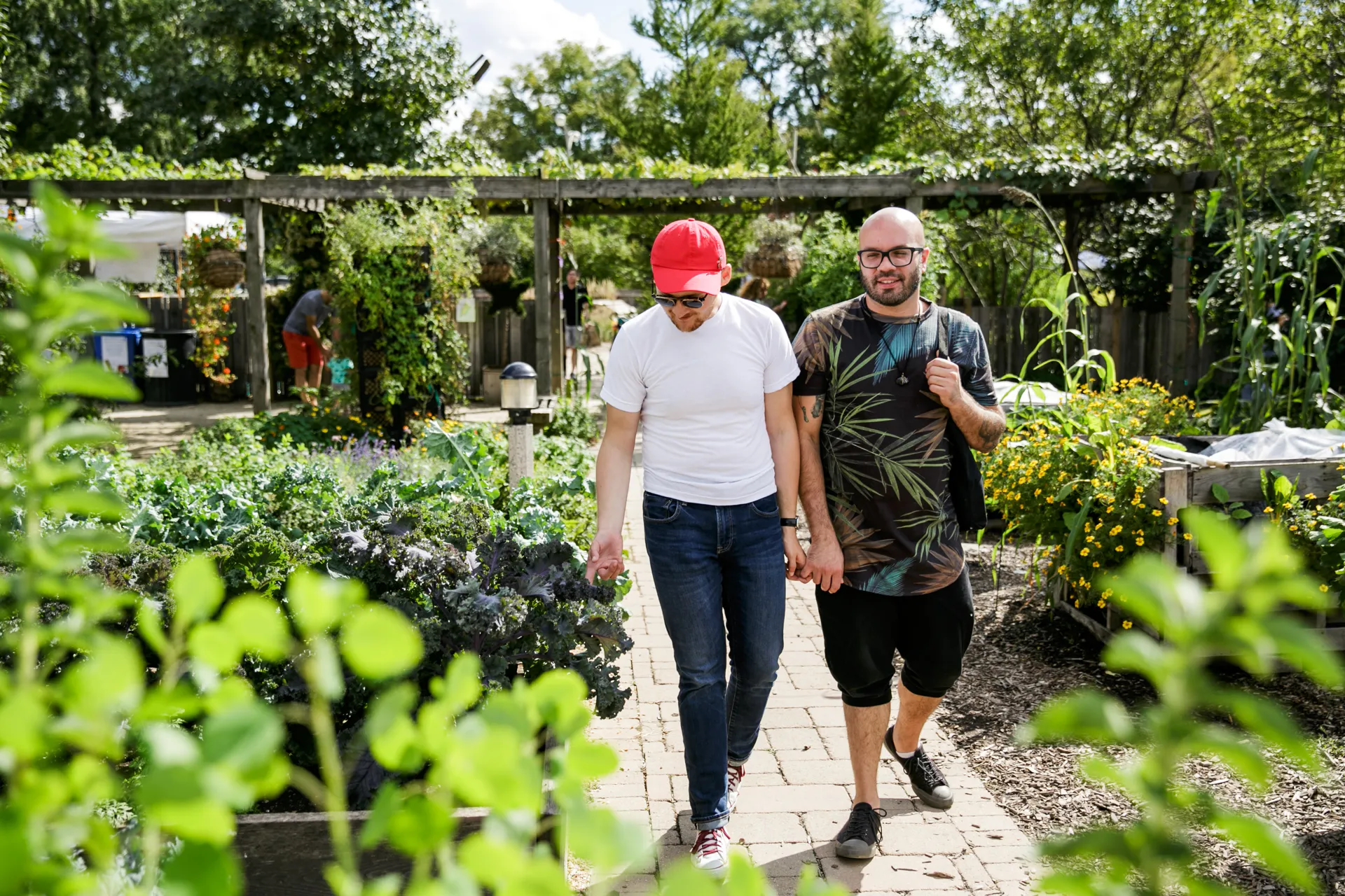 Two people walking through the Demonstration Garden outside.